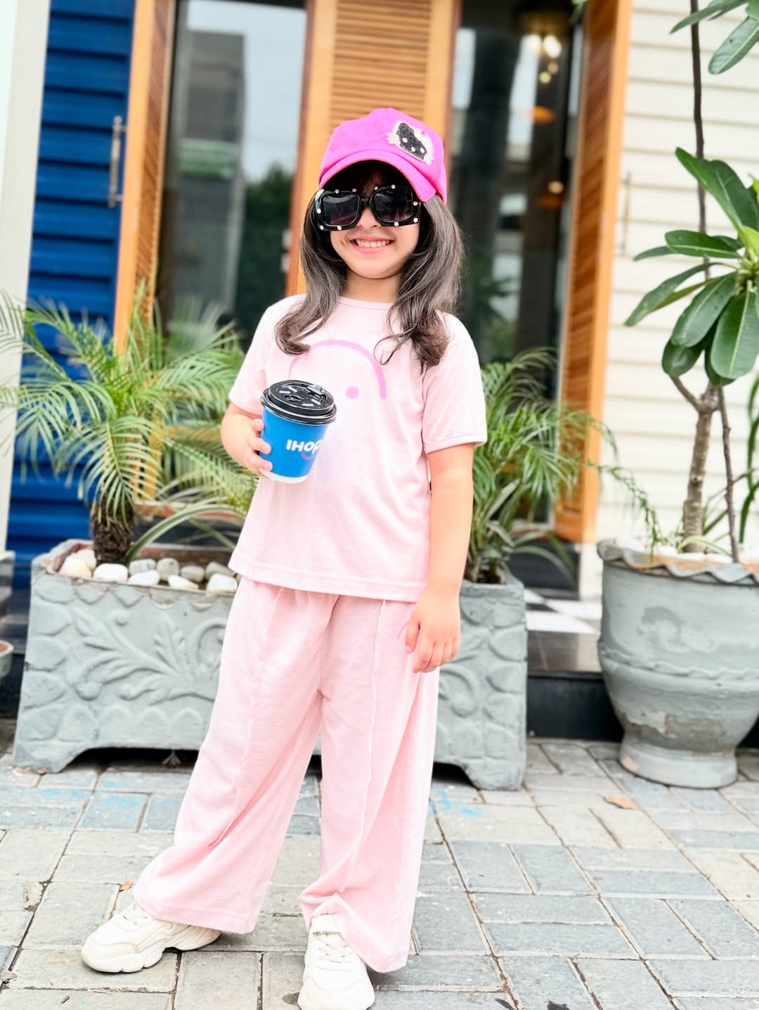 Young girl wearing pink t-shirt and pants co-ord set with pink cap and sunglasses, showcasing comfortable kids' fashion